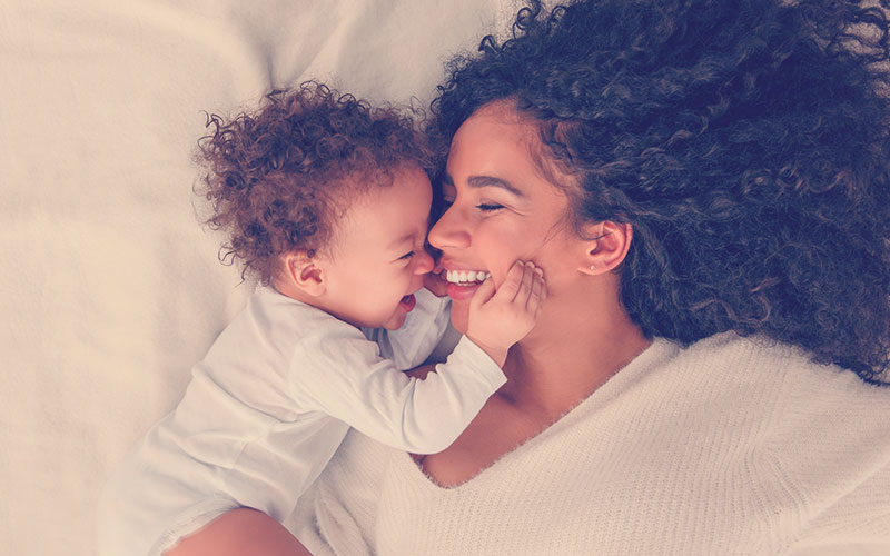 Mamá con cabello crespo y su hijo sonriendo