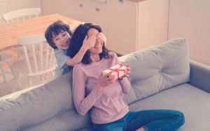 Niño sorprendiendo a su mamá con un regalo