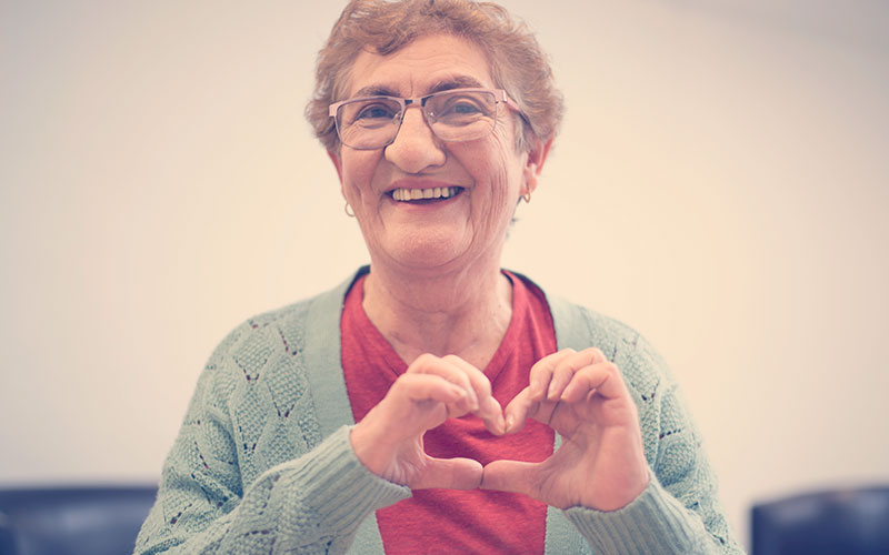 Persona mayor realizando un corazón con sus manos