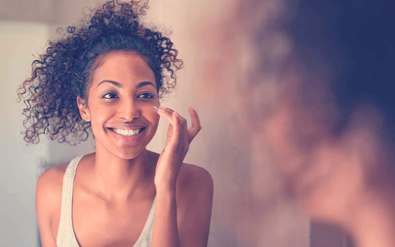 joven aplicándose crema en la mejilla