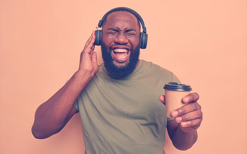 un hombre optimista con barba gruesa siente escuchas energizadas audio vía audífonos