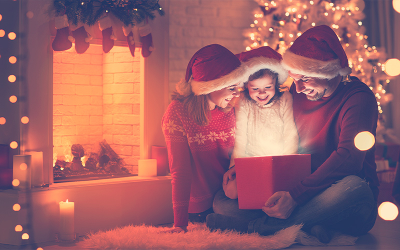 papás e hija abriendo un regala en Navidad