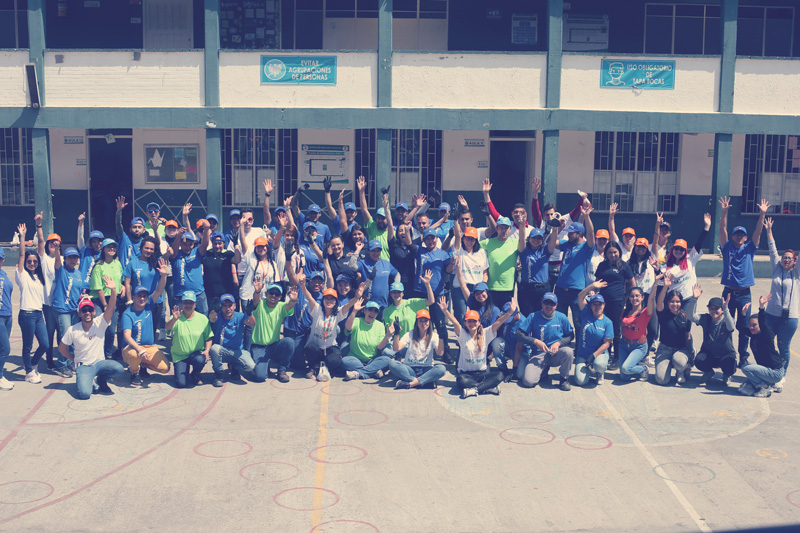 Grupo de voluntarios sonrientes alzando las manos.