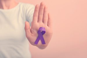 Mano con cinta morado haciendo referencia al Día Internacional de la Eliminación de la Violencia contra la Mujer