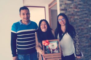 Familia compuesta por una madre y sus dos hijos adultos, muy felices recibiendo su nueva casa