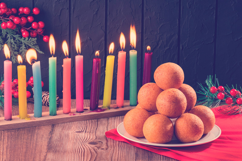 mesa de novena decorada con velas y con un plato de buñuelos