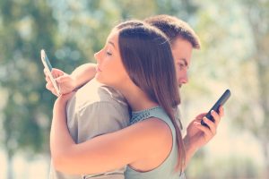 pareja mirando el celular mientras se abrazan