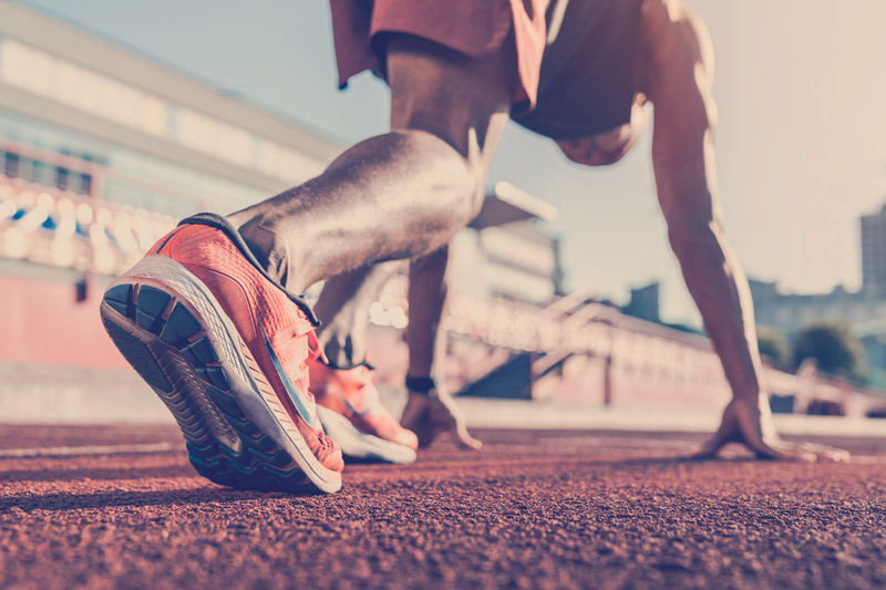 Atleta en posicion de iniciar una carrera en un campo de atletismo.