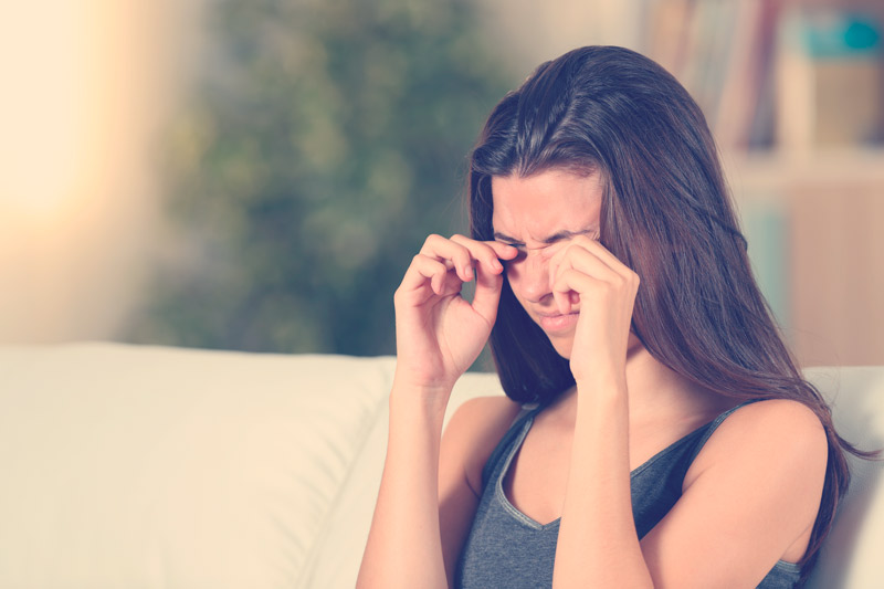 mujer tiene una molestia en los ojos