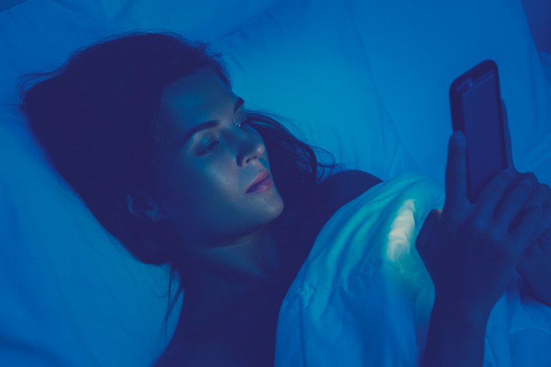 mujer en la noche mirando el celular antes de dormir 