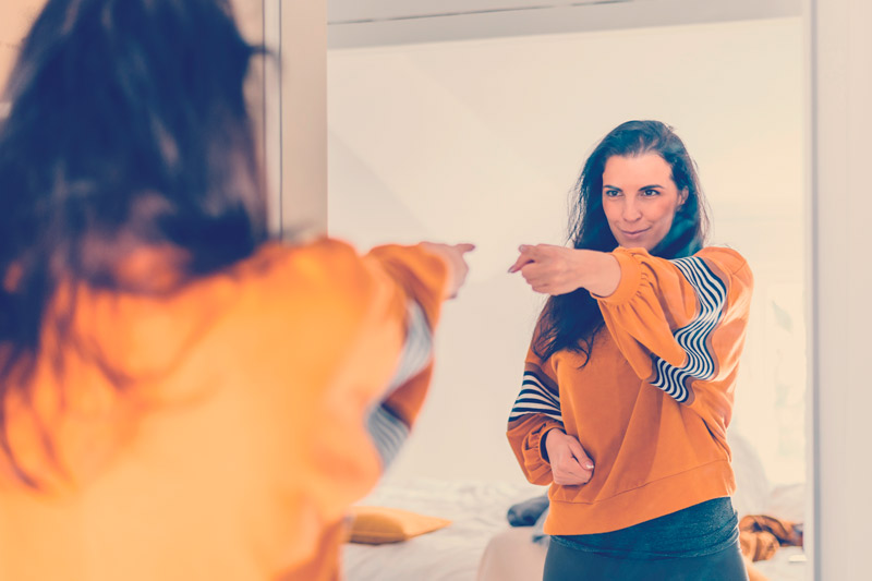 mujer frente al espejo proponiéndose lograr metas implementando micro hábitos