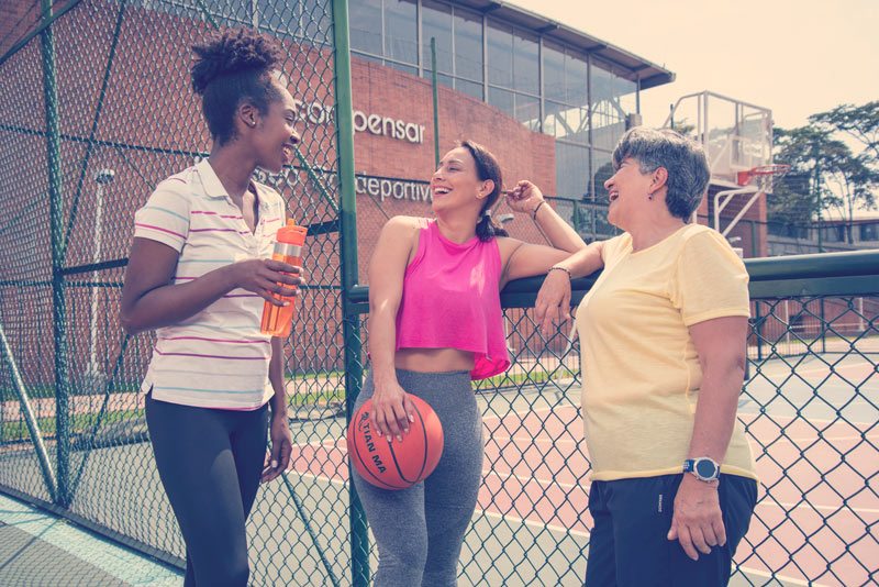 Tres mujeres de diferentes grupos de edades, hablando muy alegres despues de su entrenamiento.