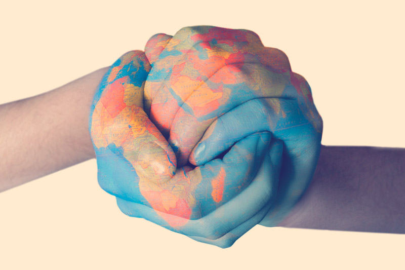 Dos manos unidas pintadas con el mapa del mundo