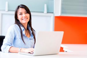 mujer emprendedora feliz sentada frente a un computador portátil