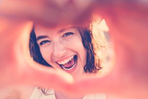 mujer sonriendo haciendo un corazón