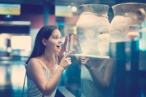 joven sonriente considera exhibiciones en el museo