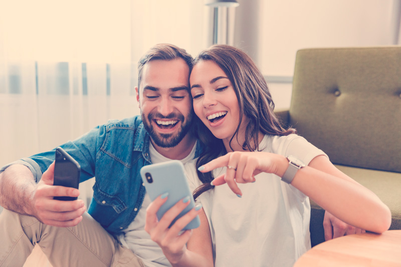 Hermosa pareja joven enamorada en casa, sentada en la sala de estar, 