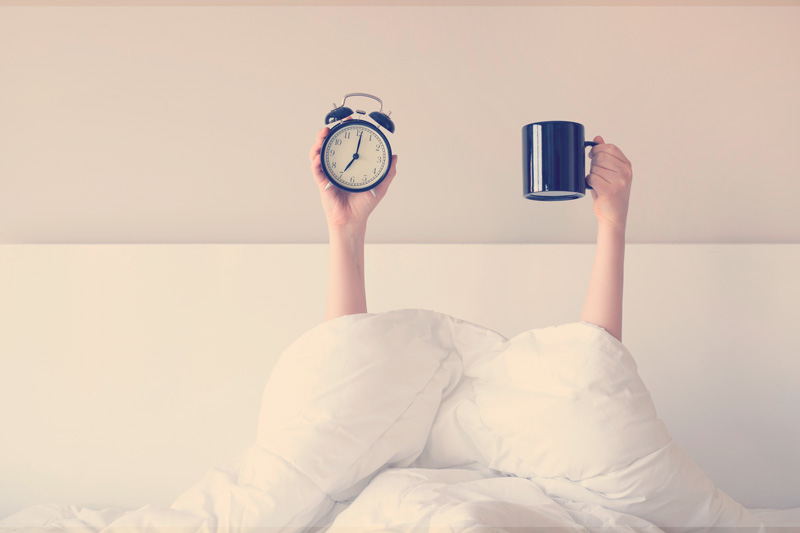 Mujer mostrando un brazo levantada sosteniendo una taza de café