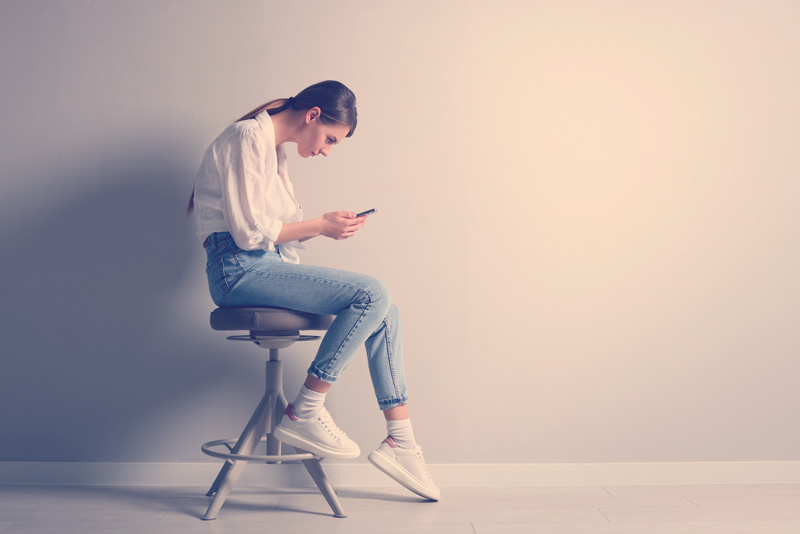 mujer encorvada mirando el celular