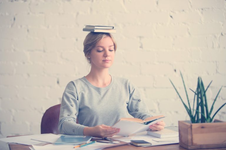 mujer en el escritorio con libros en la cabeza,