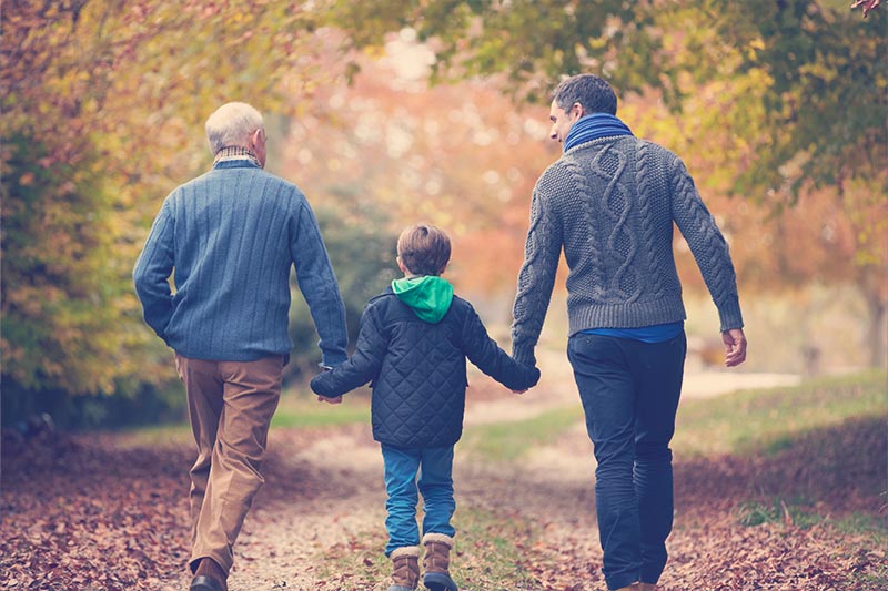 abuelo, nieto e hijo caminan por el bosque