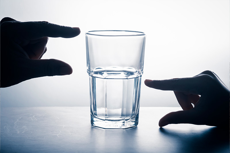 Medición de las manos en vidrio que tiene una parte vacía y agua izquierda, 