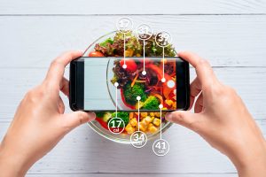 manos en celular toma foto de verduras y cuenta calorías