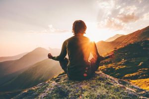 hombre meditando en la montaña