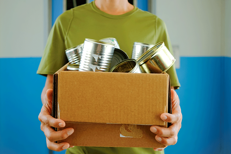 hombre que sostiene caja de carton marron de latas de metal