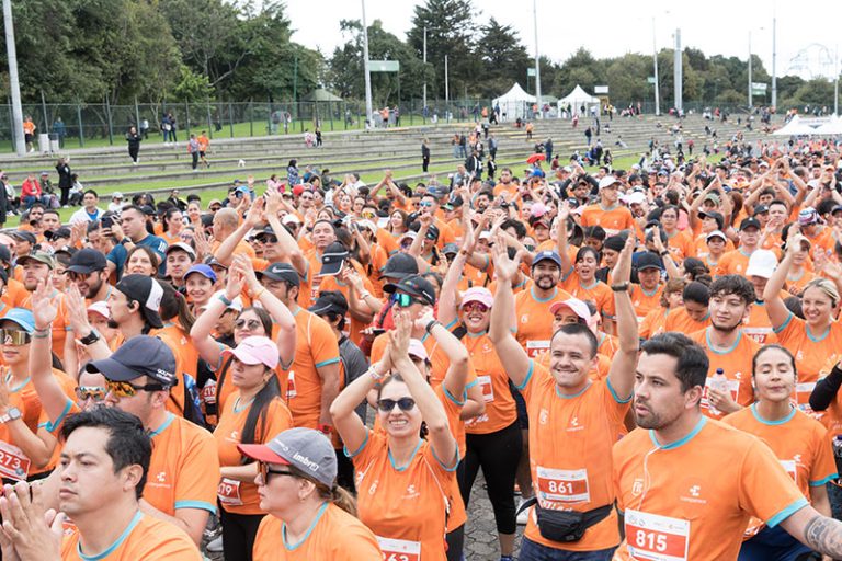 participantes de la carrera en grupo vistiendo camisetas de color naranja