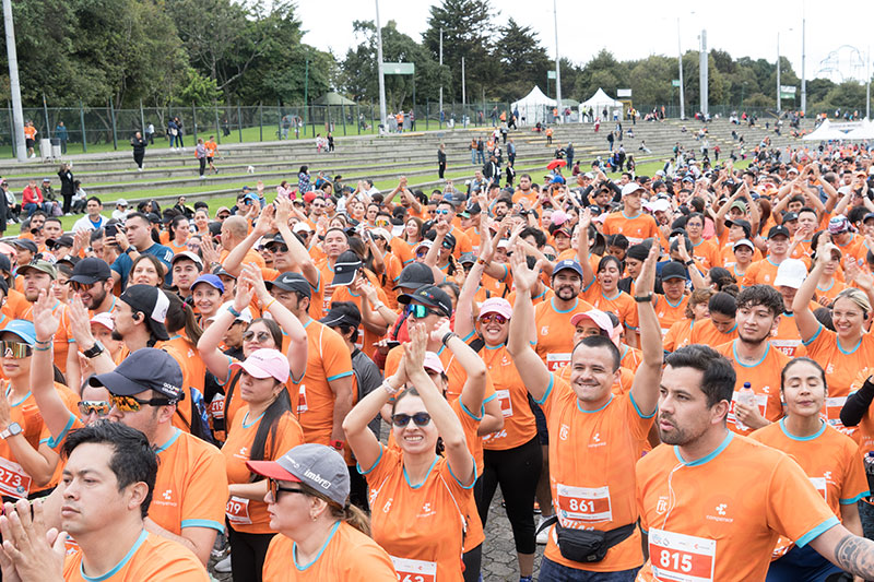 participantes de la carrera en grupo vistiendo camisetas de color naranja