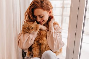 mujer sonriente jugando con su gato