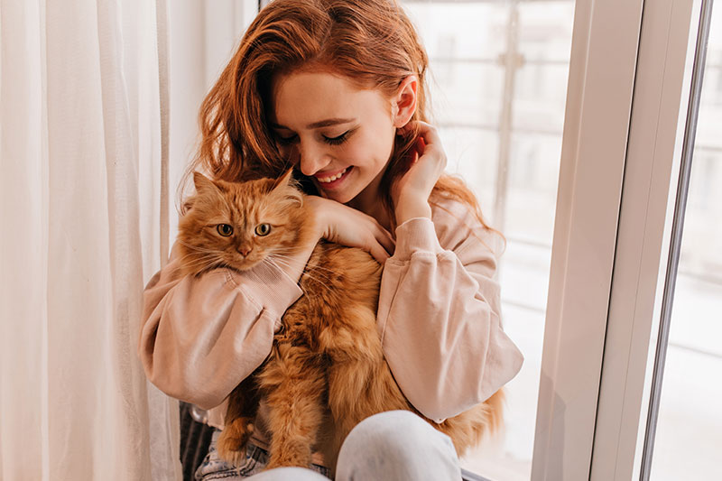 mujer sonriente jugando con su gato