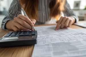 Contador revisando documentos para la declaración de renta 2026 de grandes contribuyentes frente a una calculadora.