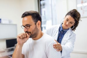 Hombre con tos persistente en consulta médica para diagnóstico de síntomas de la tuberculosis.