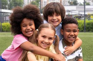 Grupo de niños diversos abrazándose y sonriendo, representando la alegría y los juegos creativos para niños durante el Día de la Niñez.