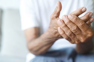 Persona de la tercera edad con rigidez y temblor en las manos, síntoma motor temprano de la enfermedad de Parkinson.