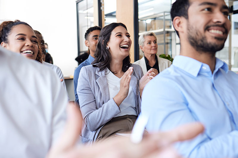 Grupo de empleados sonrientes en una charla sobre salud de los trabajadores y bienestar empresarial.