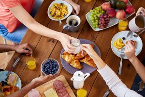 Mesa de brunch en casa con variedad de frutas, croissants, café y jugo de naranja compartida con amigos.