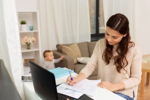 Madre profesional liderando la planificación financiera de su hogar en Colombia con un bebé al fondo, concepto de estabilidad y economía familiar 2026.