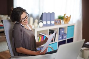 Mujer organizando su área de trabajo en casa usando una silla ergonómica y escritorio ordenado, que son clave para organizar el area de trabajo en casa.