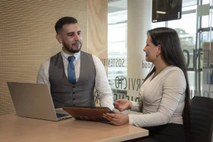 Dos profesionales de un Centro de Servicios Compartidos en Colombia conversando en una oficina con laptops y tablets.