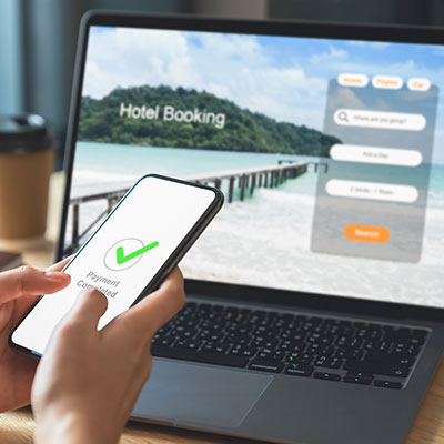 persona usando un computador portátil y un teléfono móvil para reservar un hotel