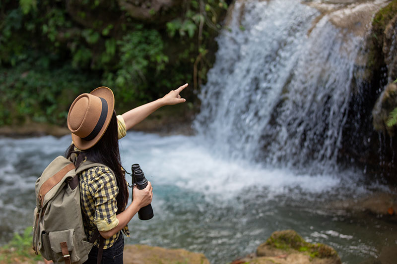 Mujer con sombrero observando una cascada haciendo ecoturismo cerca de Bogotá