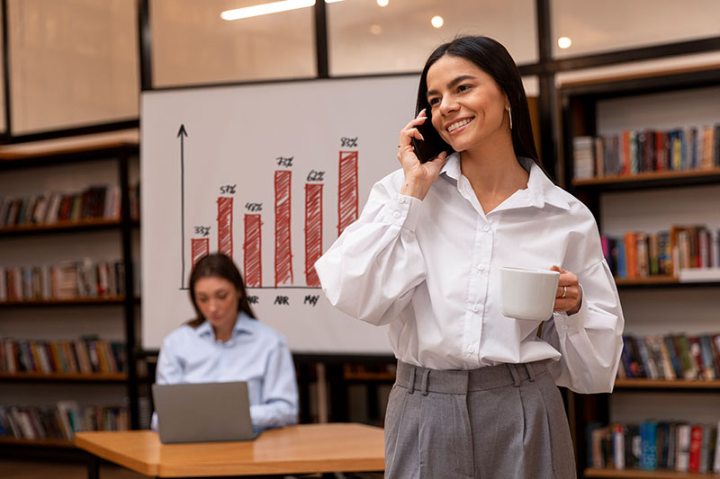 Mujer ejecutiva gestionando procesos eficientemente por teléfono mientras trabaja en una oficina moderna.
